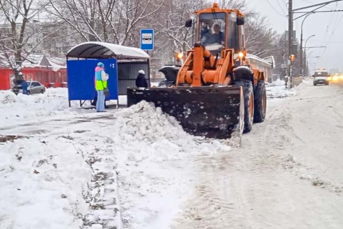 трактор расчищает снег на остановке