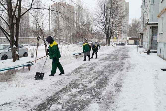 дворники чистят снег возле дома