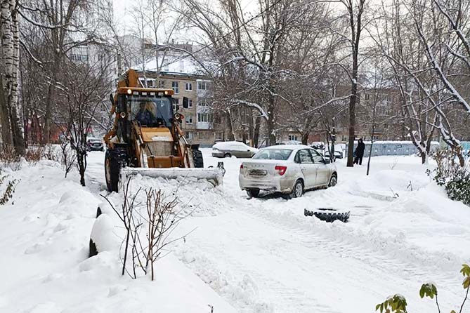 трактор расчищает снег во дворе