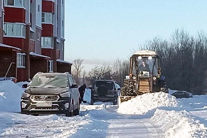 трактор расчищает снег на дворовой территории