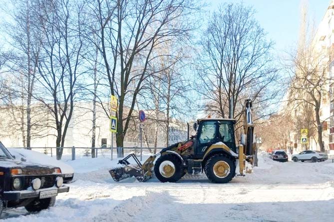 трактор расчищает снег во дворе