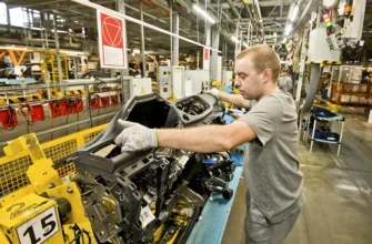 рабочий монтирует двигатель автоваз