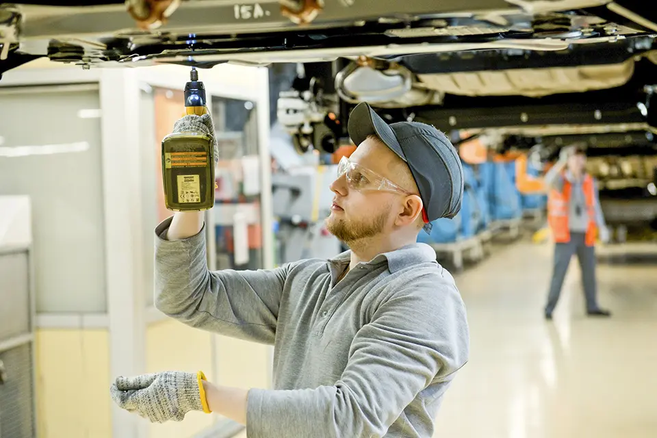 рабочий работает с кузовом лада веста