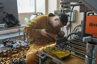 обрабатывает деталь болгаркой