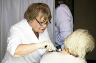 врач-онкоголо осматривает кожу женщины