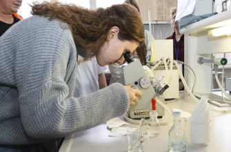 старшеклассница смотрит в микроскоп