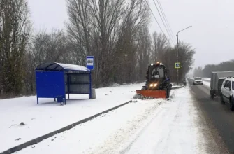 трактор чистит дорогу возле остановки
