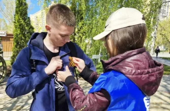 молодой человек прикрепляет георгиевскую ленту