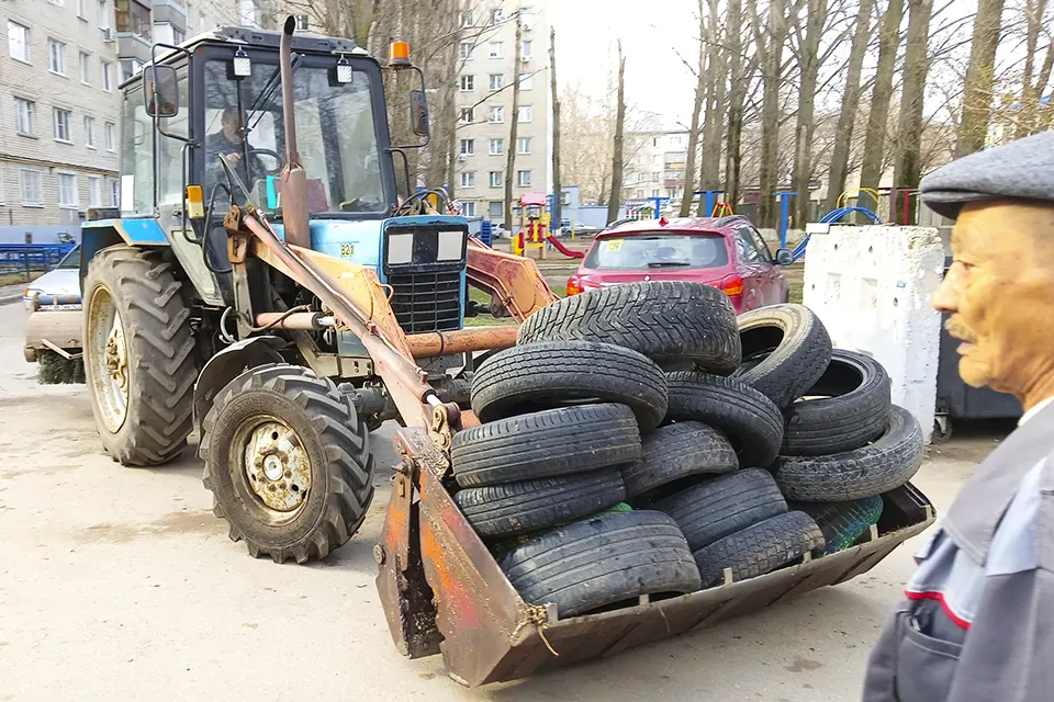 трактор вывозит покрышки со двора