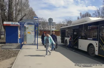женщина с телефоном вышла из автобуса на остановке