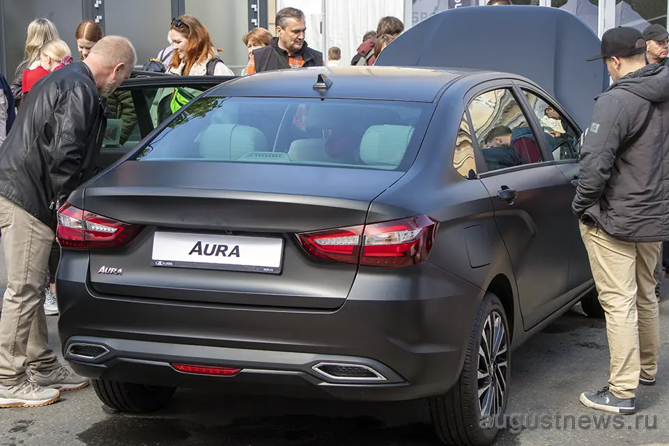 новый автомобиль аура черного цвета рассматривают покупатели