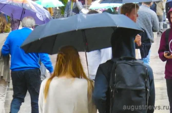 девушка и парень идут под одним зонтом в дождь