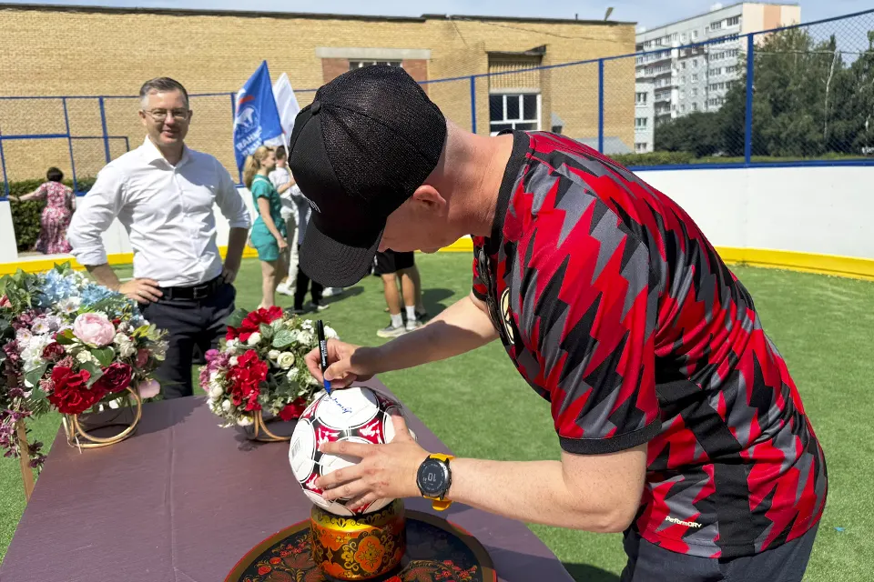 футболист ставит автограф на мяче