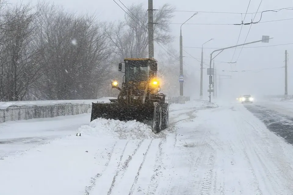 трактор убирает снег на дороге
