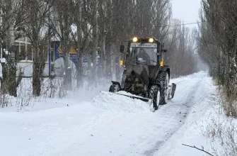 трактор расчищает тротуар от снега